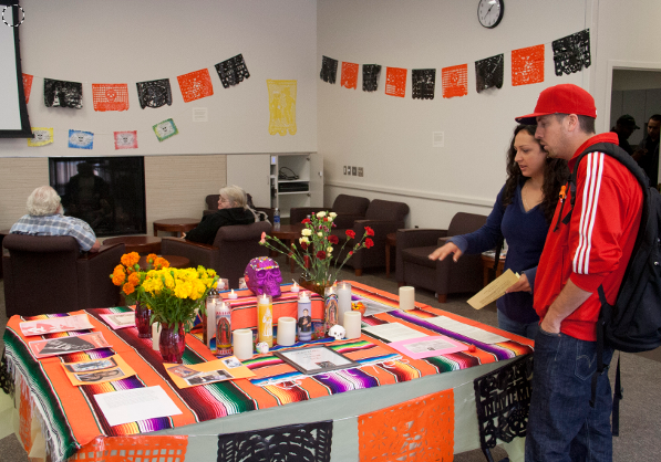 Students at the Multicultural Center taking a look at one of the tables made available for students to place photos and other items, in memory of loved ones.   