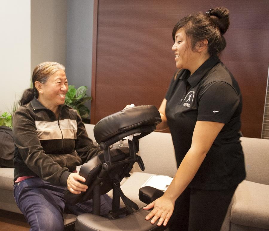 Massage therapy graduate Jeanelle Diaz provides a free massage for ESOL student Yee Win at the health fair.