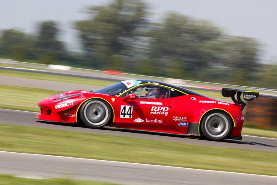 A red racing car is seen here on a race track during daytime.