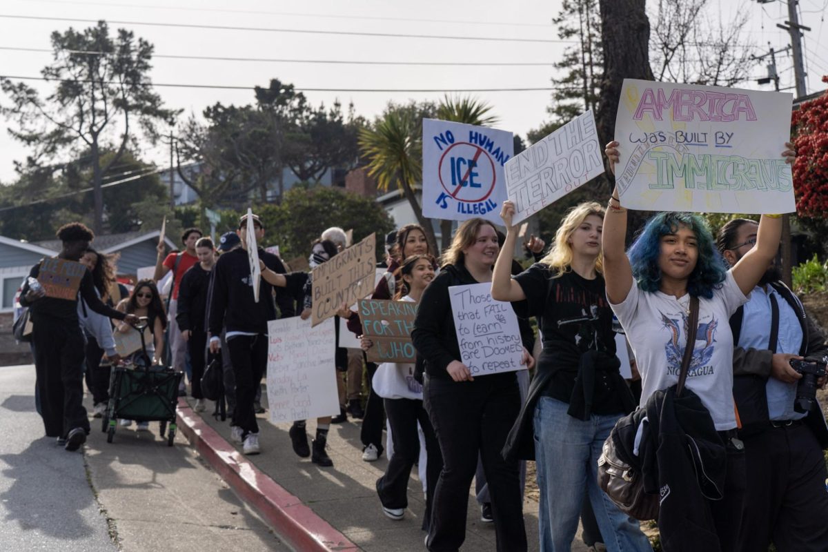 Students hold signs up and chant as they protest through local San Mateo neighborhood.