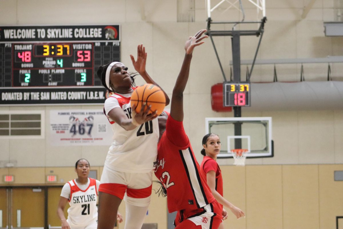 Trojans sophomore center Imaya Anderson drives to the basket for a layup as a Rams defender tries to stop her.