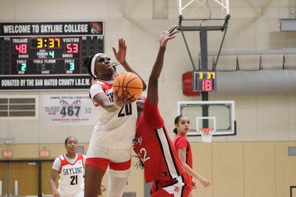 Trojans sophomore center Imaya Anderson drives to the basket for a layup as a Rams defender tries to stop her.