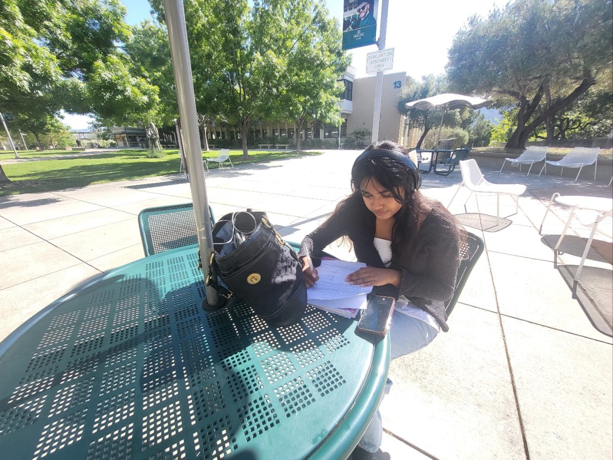 Cañada College student Diana Infante-Gutierrez listens to music while working on homework by herself on campus.